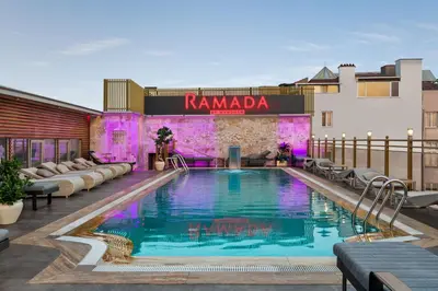 a hotel pool with lounge chairs and a building at Ramada By Wyndham Istanbul Pera Taksim in Istanbul