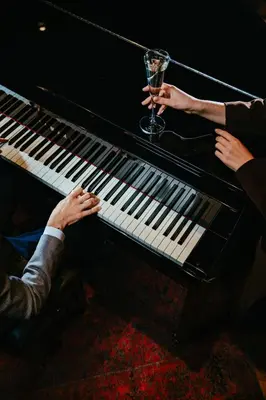 a person holding a glass of wine sitting on a piano at The Marmara Pera in Istanbul