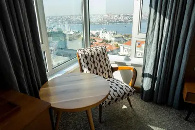 a room with a chair and a table in front of a window at The Marmara Pera in Istanbul
