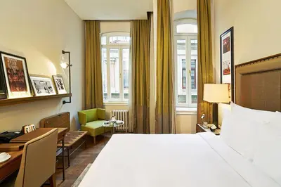 a hotel room with a large bed and a green chair at The Bank Hotel Istanbul, a Member of Design Hotels in Istanbul