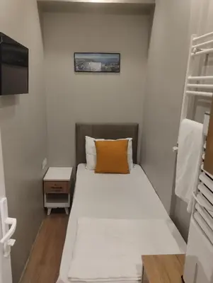 a small bedroom with a bed with a orange pillow at Mr Lion Kumkapı Otel in Istanbul