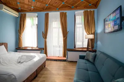 a bedroom with a bed and a couch and windows at Taksim Antique Hotel in Istanbul