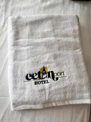 a white towel with a logo on a bed at Cetin Port Hotel in Istanbul