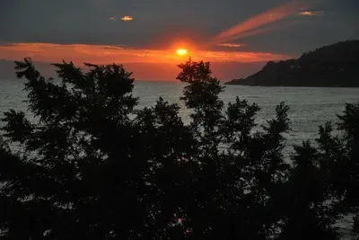 a sunset over a body of water with trees at Mola Hotel in Marmara Adasi