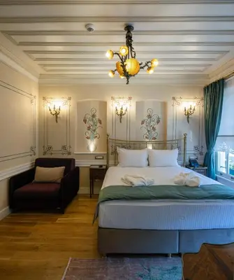 a bedroom with a bed and a chair and a chandelier at Hotel Turkish House in Istanbul