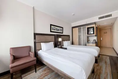 a hotel room with two beds and a chair at Ramada Plaza By Wyndham Istanbul City Center in Istanbul