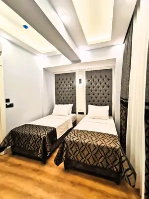 two beds in a room with white walls and wood floors at Luxx Garden Hotel in Istanbul