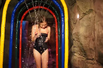 a young girl in a bathing suit standing in a water tunnel at Almira Hotel Thermal Spa & Convention Center in Bursa