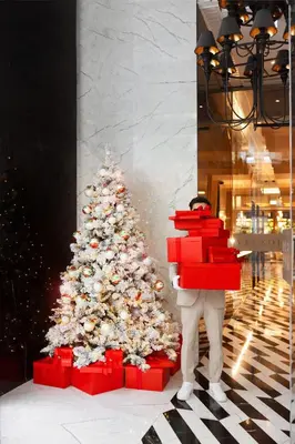 a person holding a stack of presents in front of a christmas tree at Vakko Hotel and Residence in Istanbul