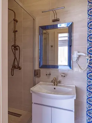 a bathroom with a sink and a mirror and a shower at Ragip Pasha Apartments in Istanbul