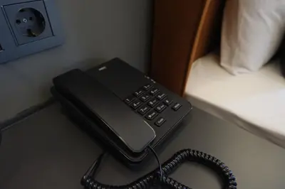 a black phone sitting on a desk next to a bed at The Pearl Airport Hotel in Arnavutköy