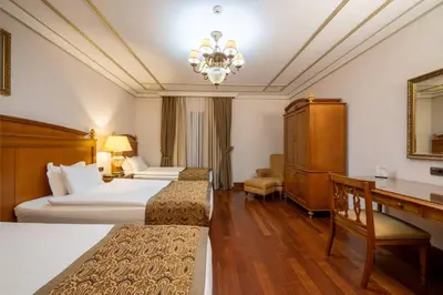 a hotel room with two beds and a desk at The Central Palace Taksim in Istanbul