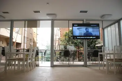 a flat screen tv in a room with tables and chairs at Bursa Park Apart Hotel in Bursa