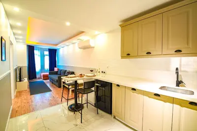 a kitchen with white cabinets and a living room at Cihangir VAV Suites in Istanbul