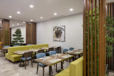 a dining room with wooden tables and chairs at Hampton By Hilton Istanbul Airport, Arnavutkoy in Istanbul