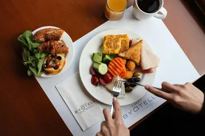 a table with a plate of food and a person holding a fork at Byotell Istanbul in Istanbul