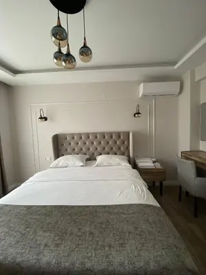 a bedroom with a large white bed and a desk at ANTİGONİA BUTİK OTEL in İznik