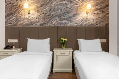 two beds with white sheets and a vase of flowers at Valide Hotel in Istanbul