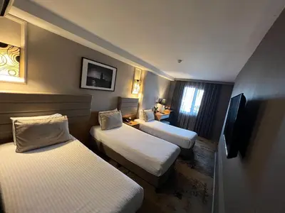 a hotel room with three beds and a tv at All Seasons Hotel in Istanbul
