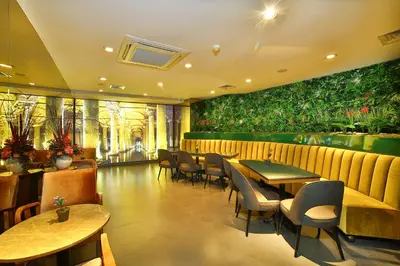 a restaurant with tables and chairs and plants on the wall at All Seasons Hotel in Istanbul