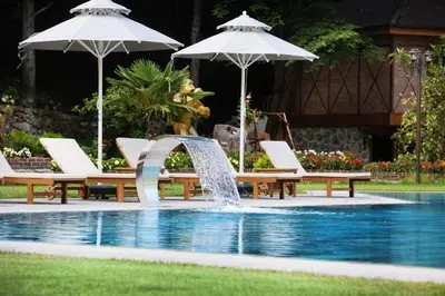 a pool with two umbrellas and chairs and a fountain at Casa Giallo Managed By Dedeman in Sapanca