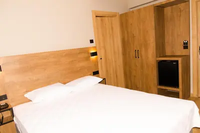 a bedroom with a white bed and a wooden headboard at Fidanoğlu Suite Hotel Çorlu in Corlu