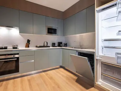 a kitchen with gray cabinets and a refrigerator at Movenpick Living Istanbul Camlivadi in Istanbul