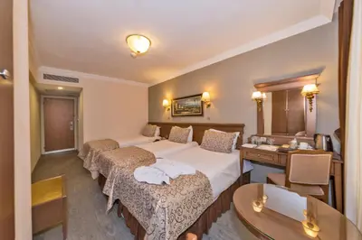 a hotel room with two beds and a desk at Laleli Gonen Hotel in Istanbul