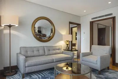 a living room with a couch and a chair and a mirror at Conrad Istanbul Bosphorus in Istanbul