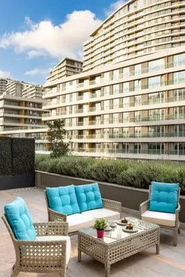 a patio with chairs and tables and a large building at The Superior Living Batışehir in Istanbul