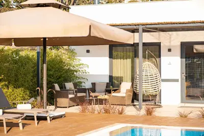 a patio with chairs and an umbrella and a pool at Pınar Otel in Erdek