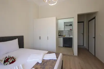 a bedroom with a white bed and a kitchen at Bonita Apart in Istanbul