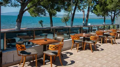 a row of tables and chairs on a patio next to the water at Lake Life Hotel in İznik