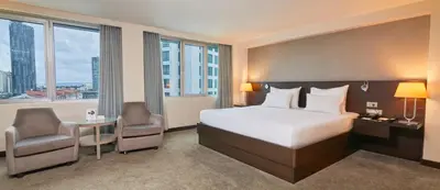 a hotel room with a bed and a desk and chairs at Dedeman Istanbul in Istanbul