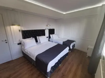 two beds in a room with white walls and wood floors at Efzen hotel in Istanbul
