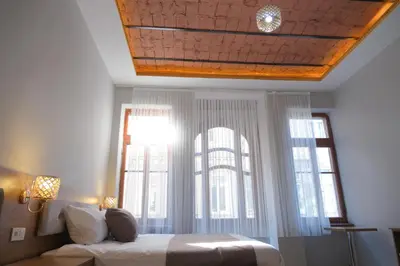 a bedroom with a bed and two large windows at Adamantides Hotel in Istanbul