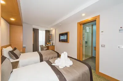 a hotel room with three beds and a bathroom at Bisetun Hotel in Istanbul