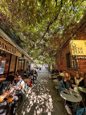 a group of people sitting at tables in an alley at Nomad Hostel Karaköy in Istanbul