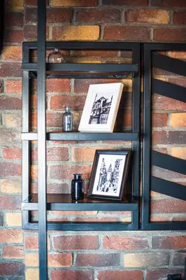 a shelf against a brick wall with two framed pictures at Mansion Gorki in Istanbul