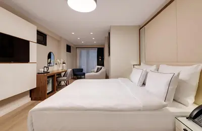 a hotel room with a large white bed and a desk at Gleam Collection Hotel in Istanbul