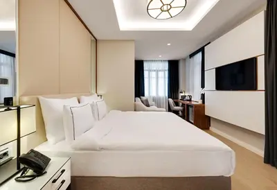 a hotel room with a large white bed and a desk at Gleam Collection Hotel in Istanbul