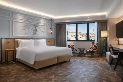 a hotel room with a bed and a woman sitting in a chair at Burdock Hotel Istanbul, Autograph Collection in Istanbul