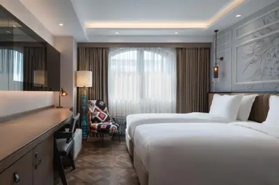 a hotel room with two beds and a desk at Burdock Hotel Istanbul, Autograph Collection in Istanbul