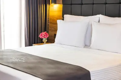 a large bed with white pillows and a vase with flowers at Marius Hotel in Istanbul