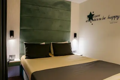 a bedroom with a bed with a green headboard at AXU AIRPORT HOTEL in Arnavutköy