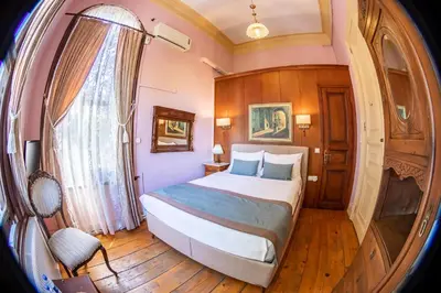 a bedroom with a large bed and a window at Büyükada Anastasia Meziki History Mansion in Buyukada