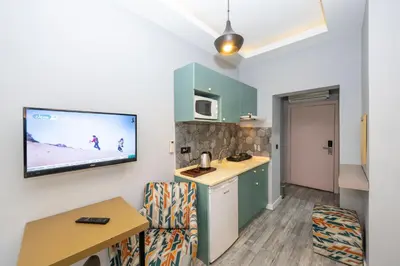 a living room with a kitchen and a tv on the wall at Cirrus Suites in Istanbul