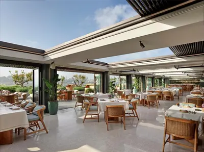 a restaurant with white tables and chairs and windows at The Peninsula Istanbul in Istanbul