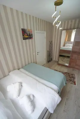 a bedroom with a bed with white sheets and a striped wall at Luxe Suite HA8 in Esenyurt