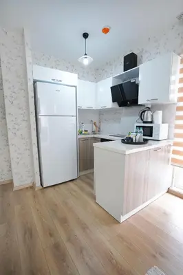 a kitchen with a white refrigerator and a wooden floor at King Suite OK0 in Esenyurt